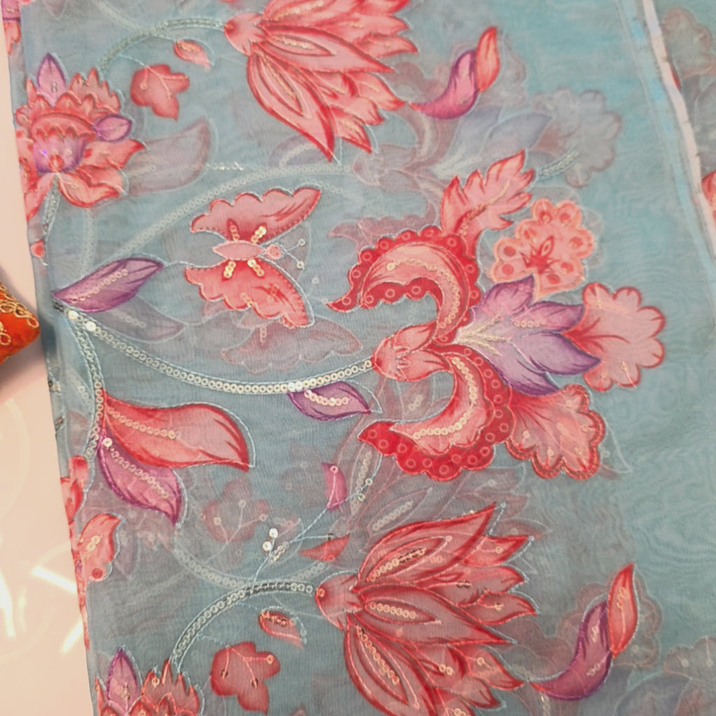Himmelblaue Organza-Sari mit Blumenpailletten und leuchtend oranger Bluse