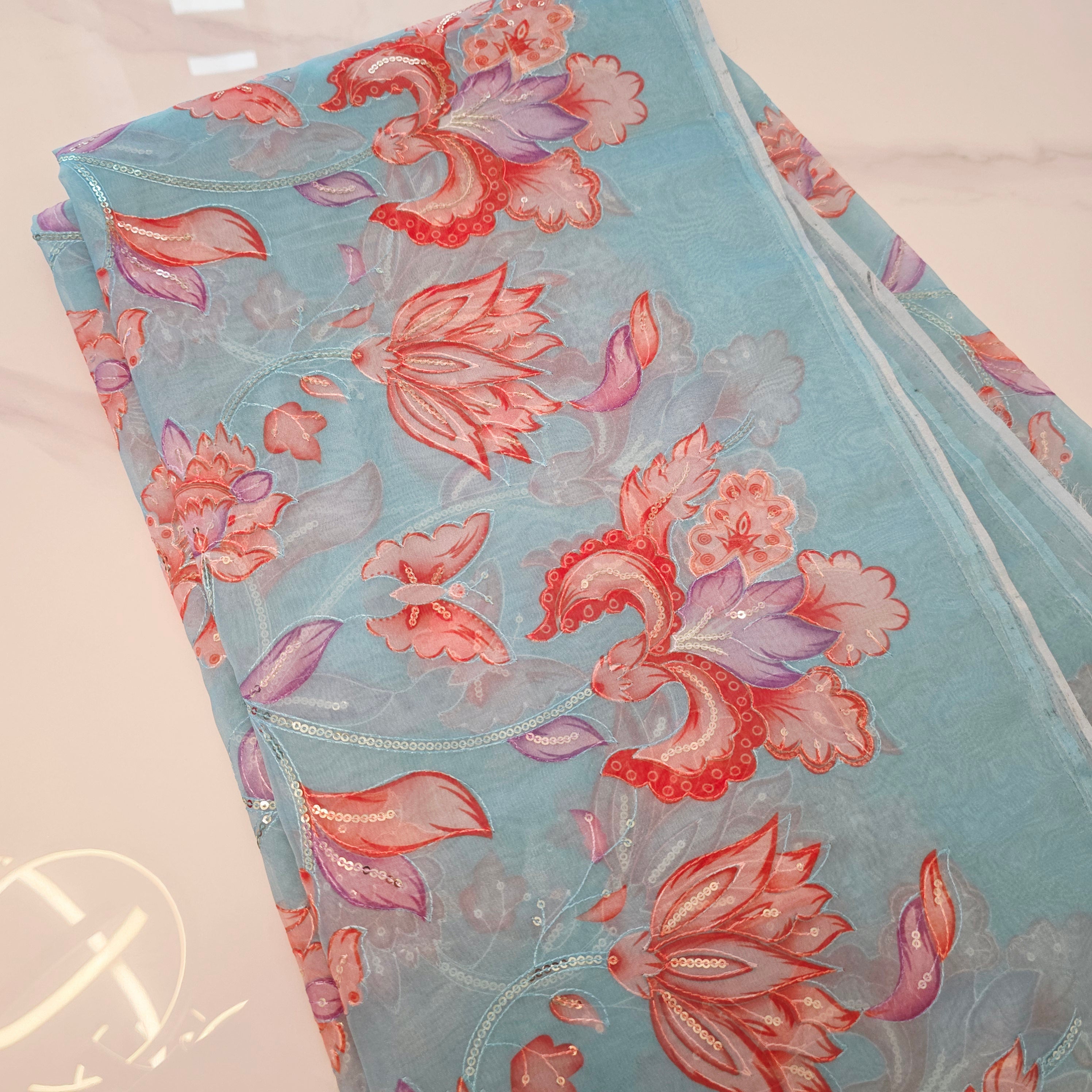 Himmelblaue Organza-Sari mit Blumenpailletten und leuchtend oranger Bluse