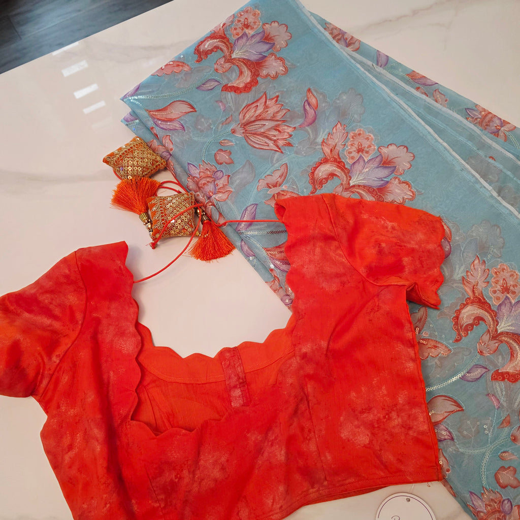 Himmelblaue Organza-Sari mit Blumenpailletten und leuchtend oranger Bluse