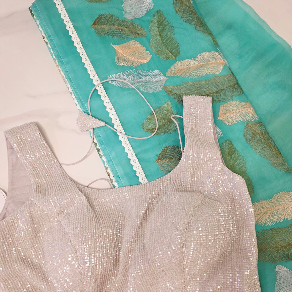 Petrolblaues Sari aus weicher Organza mit vollflächiger Blätterstickerei. Kombiniert mit einer weichen Paillettenbluse.