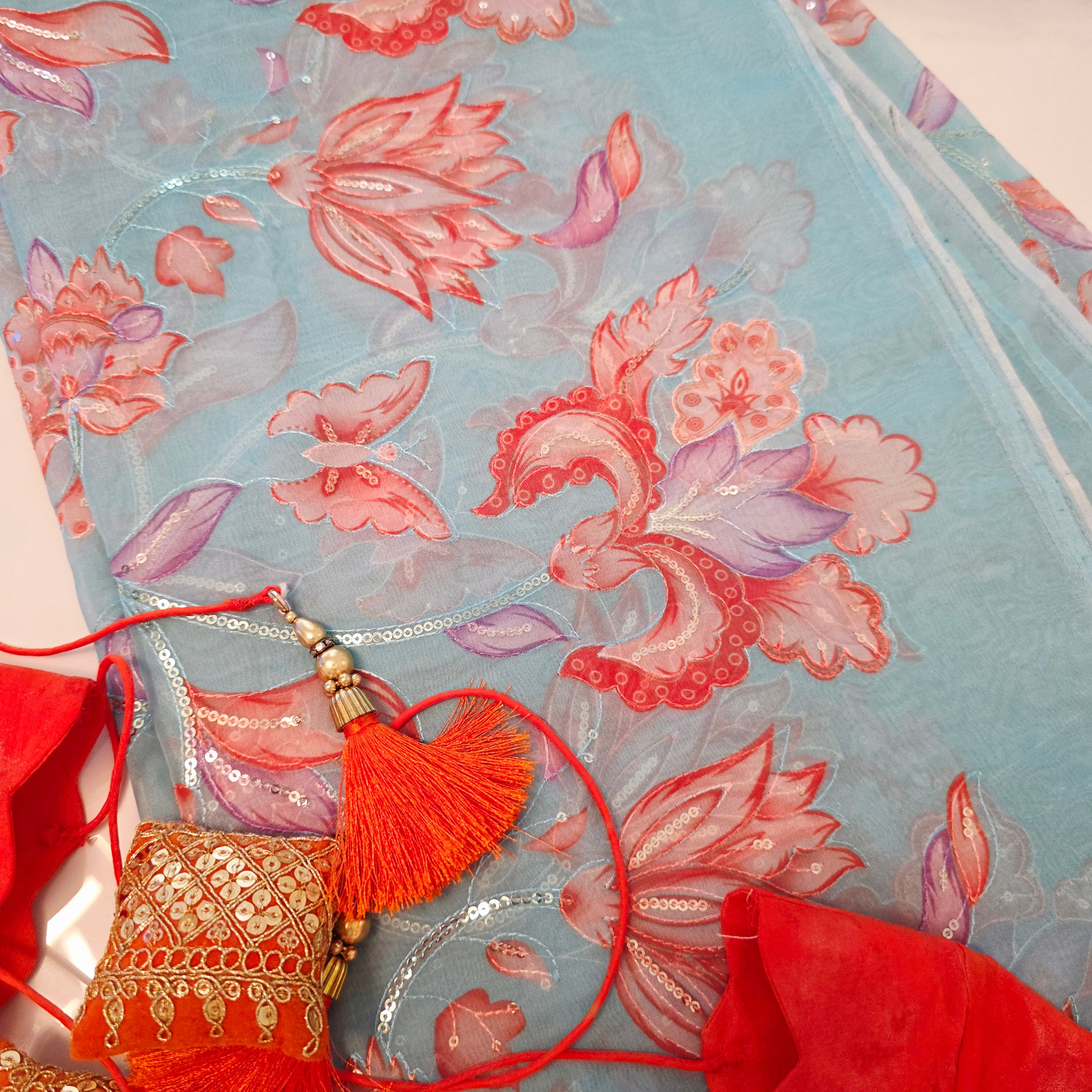 Skyblue Organza Saree with floral sequins all over paired with bright orange blouse